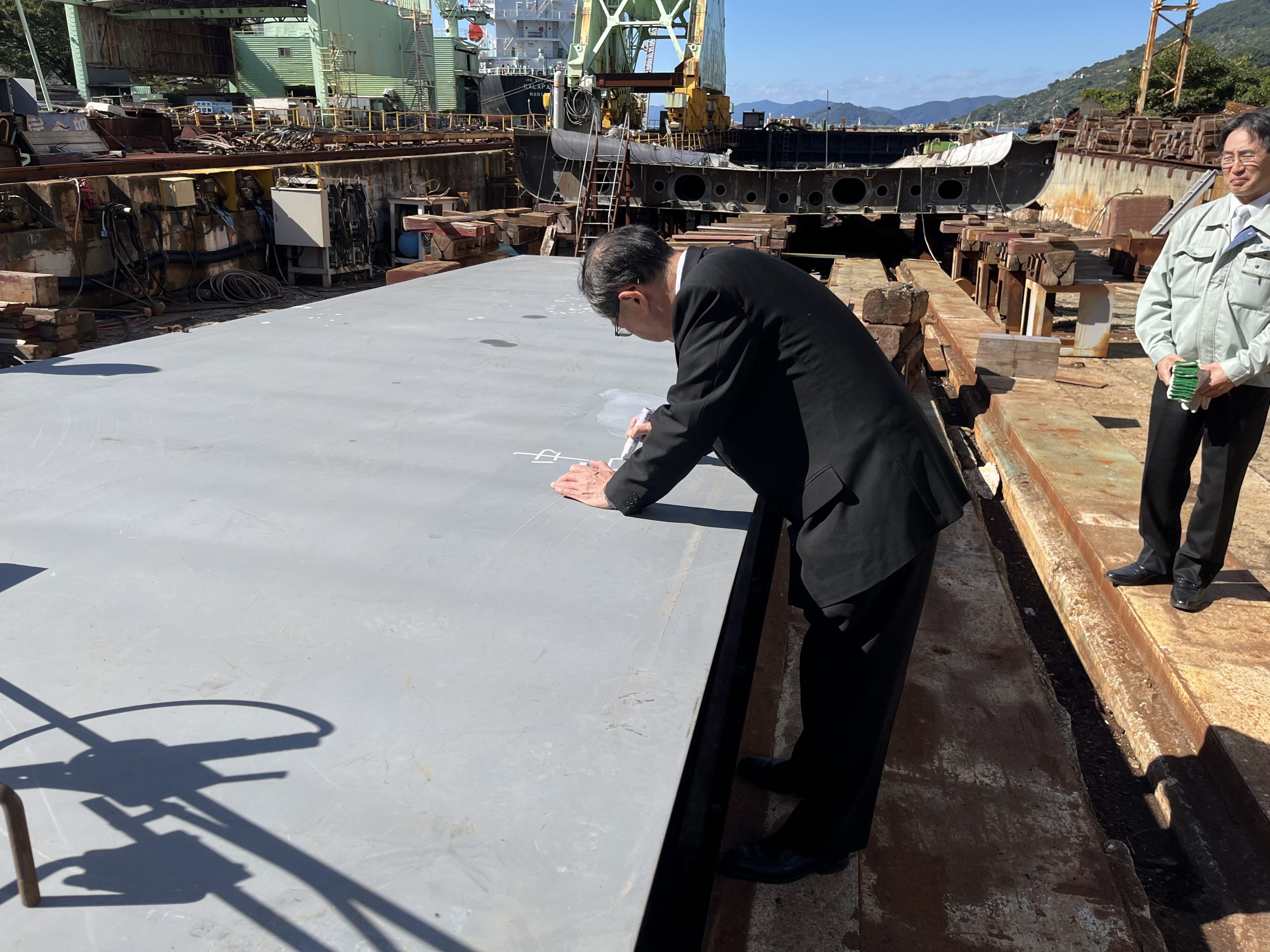 社長の中田が船の鉄板にサインする様子